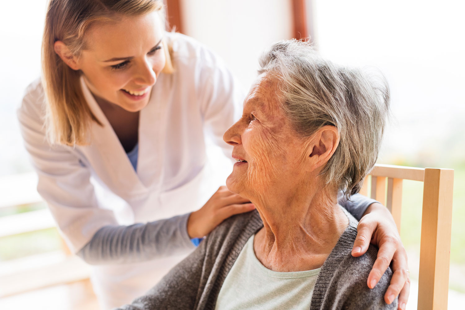 Persönliche Betreuung – eine Pflegekraft im Gespräch mit einer Seniorin zuhause
