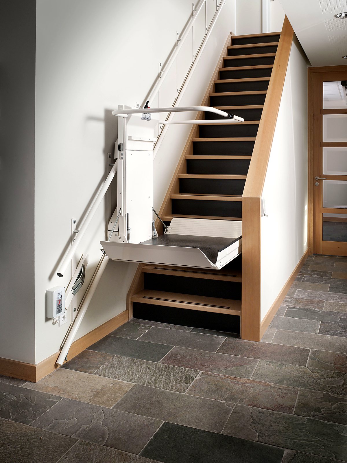 Plattformlift DELTA an einer geraden Holztreppe mit ausgeklappter Plattform
